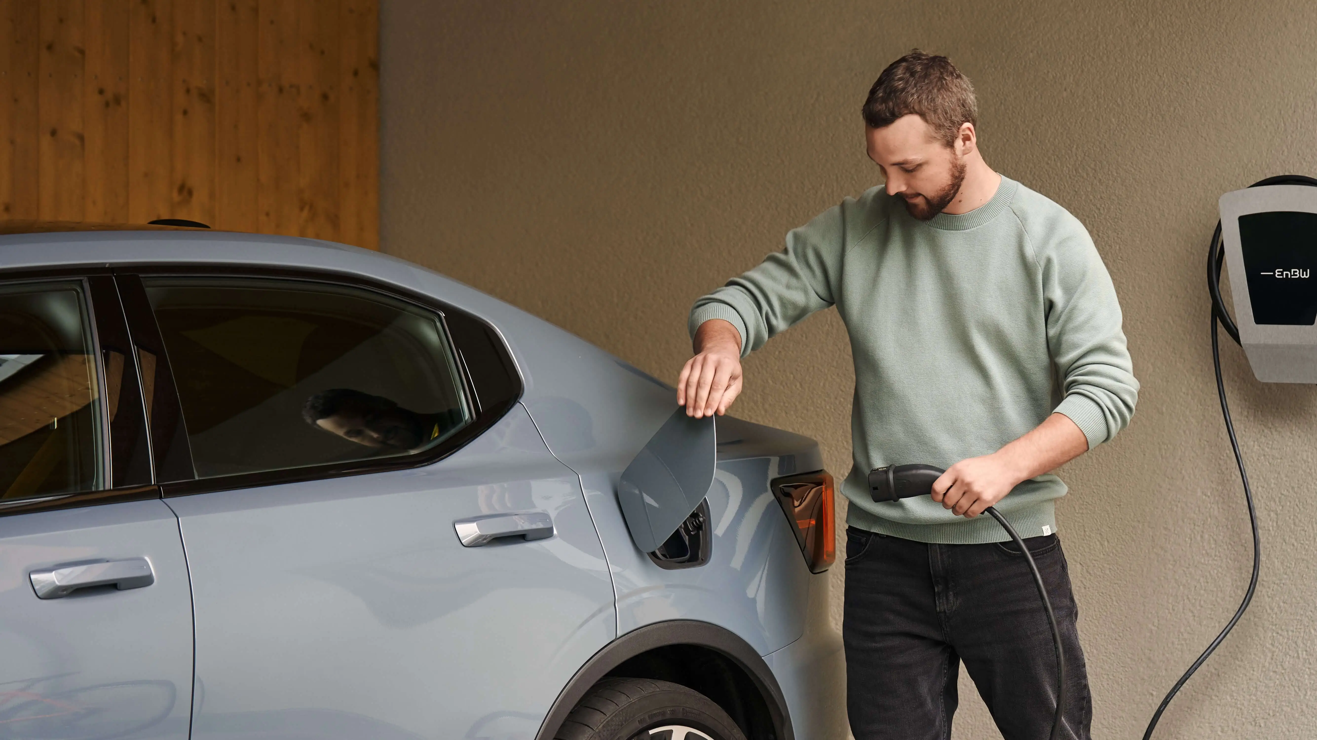Junger Mann lädt Elektrofahrzeug an Wallbox